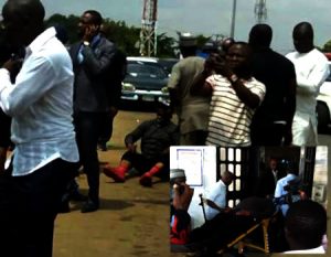 Dino Melaye seated on the ground; and on a stretcher thereafter